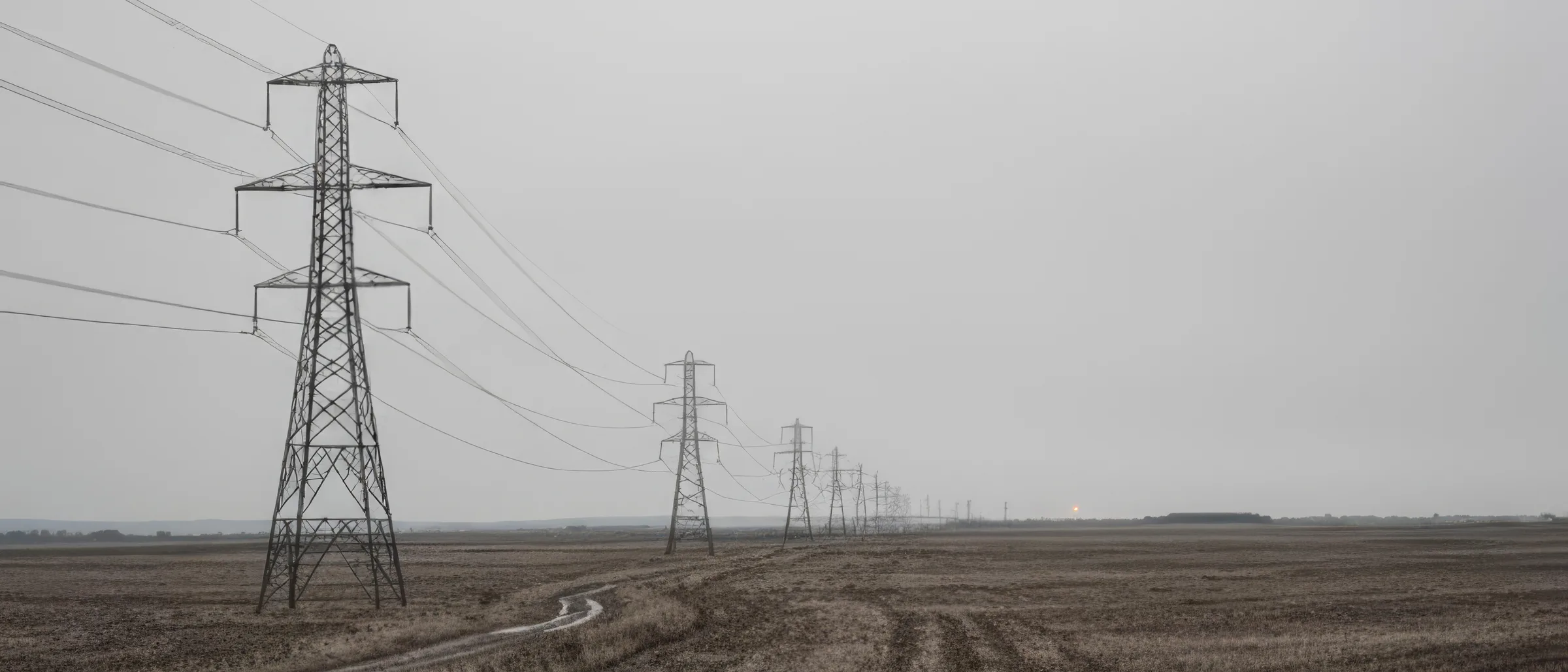 Ілюстрація: лінія опор електропередачі через рівне поле під похмурим небом