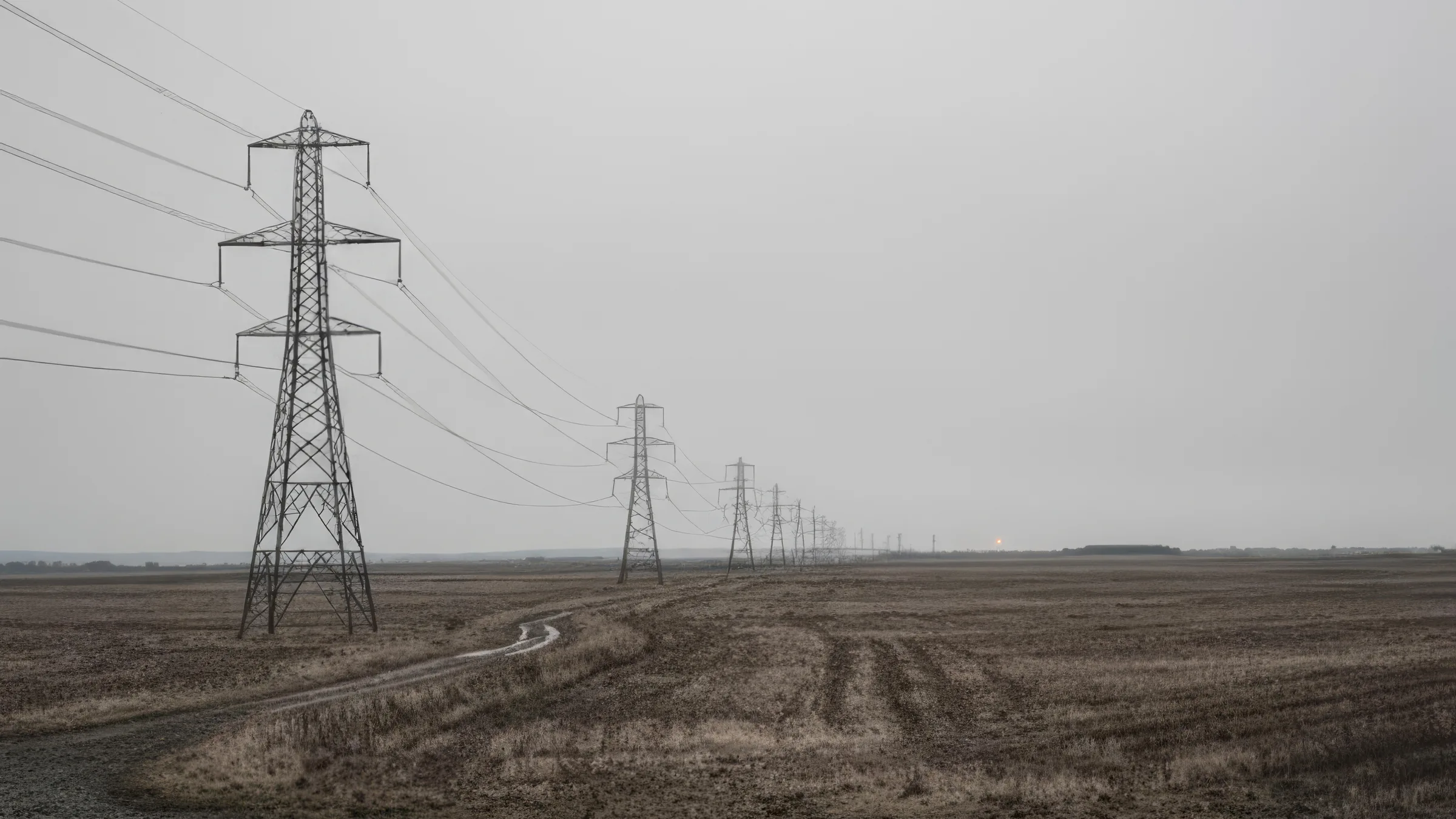 Ілюстрація: лінія опор електропередачі через рівне поле під похмурим небом
